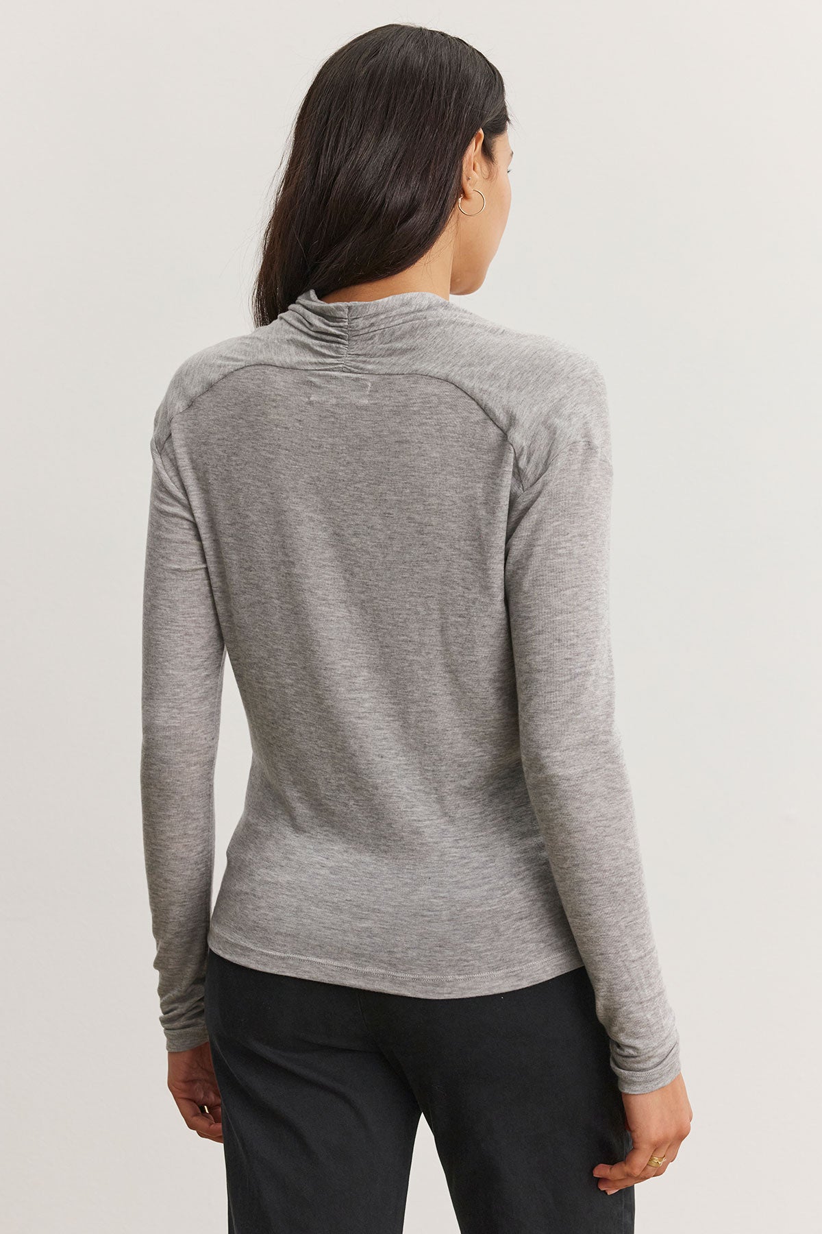   A person with long hair is seen from behind, wearing what appears to be Velvet by Graham & Spencer's gray PATTY TEE and black pants. 