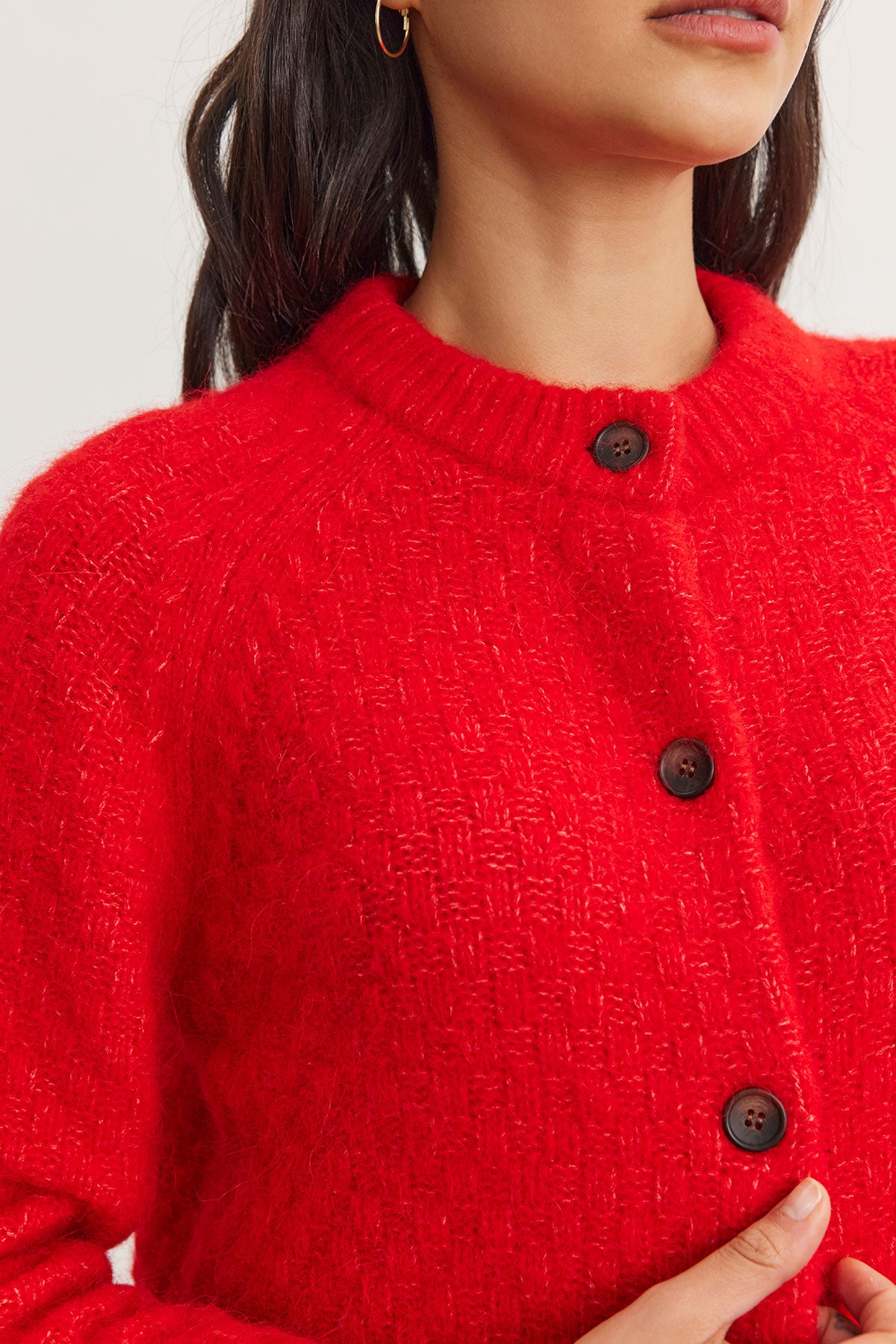 A person wearing the CHANTAL ALPACA CARDIGAN by Velvet by Graham & Spencer, crafted from a vibrant red alpaca blend and embellished with large buttons.-38301315629249