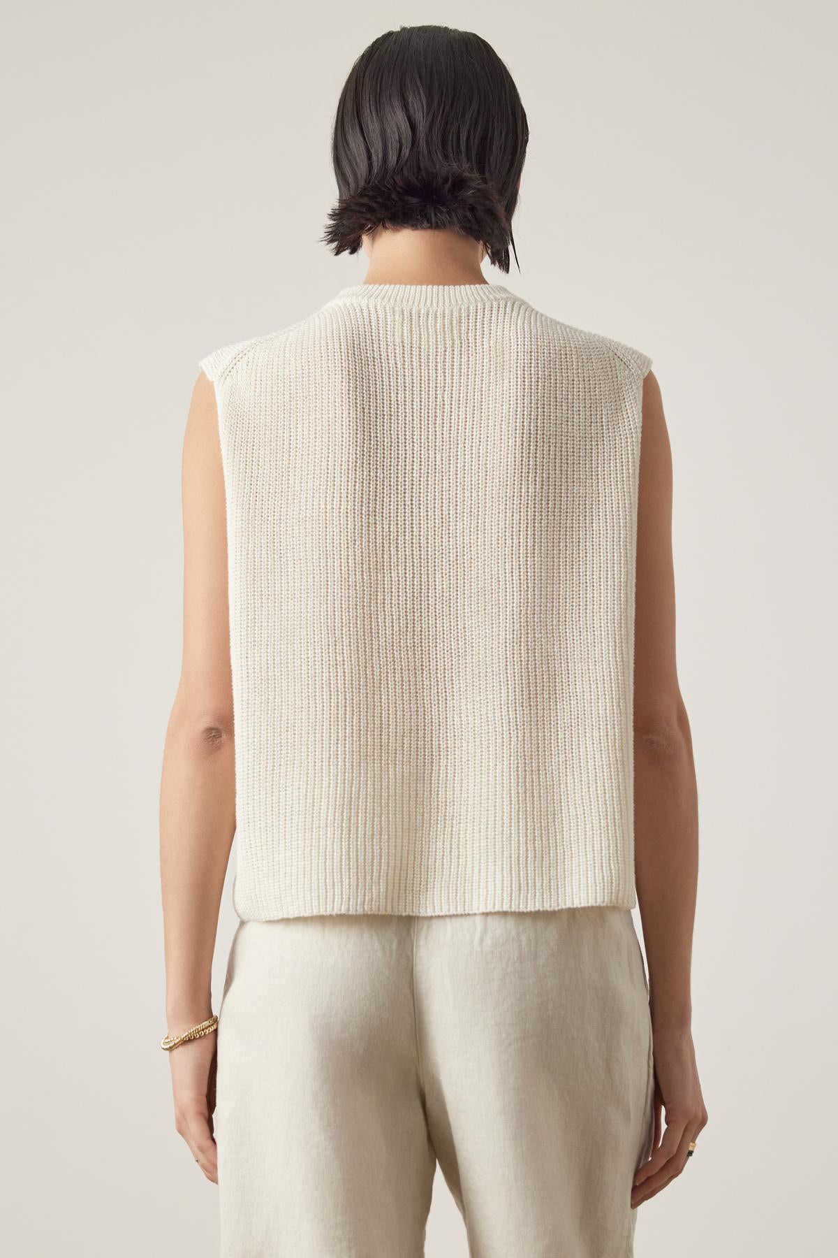   Person with short dark hair seen from the back, wearing the Velvet by Jenny Graham GARDENA LINEN SWEATER VEST and light-colored pants, crafted from breathable linen for a relaxed fit. 