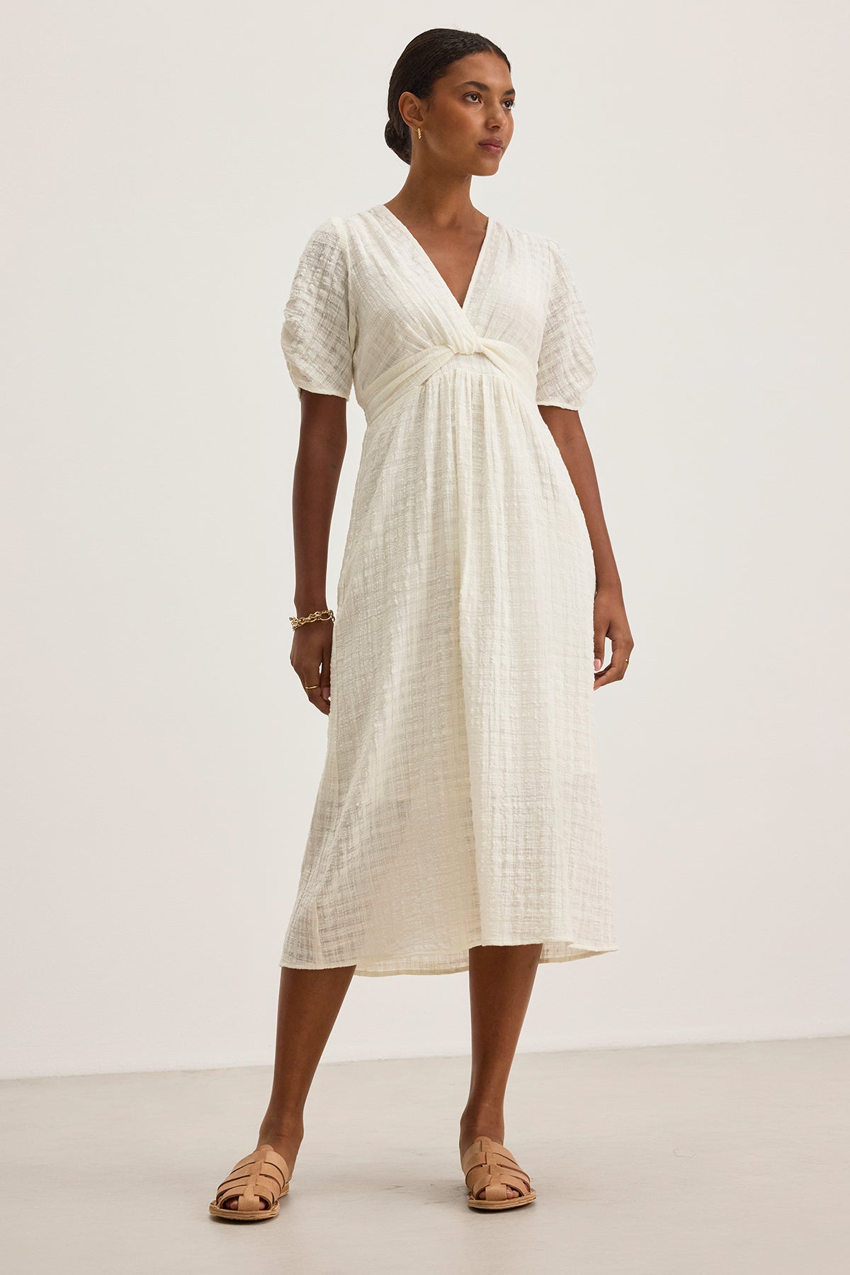 Someone is wearing Velvet by Graham & Spencer's Eloise Textured Cotton Gauze Dress, a white midi dress with a V-neckline and short sleeves, paired with beige sandals on a plain background.-38662664159425