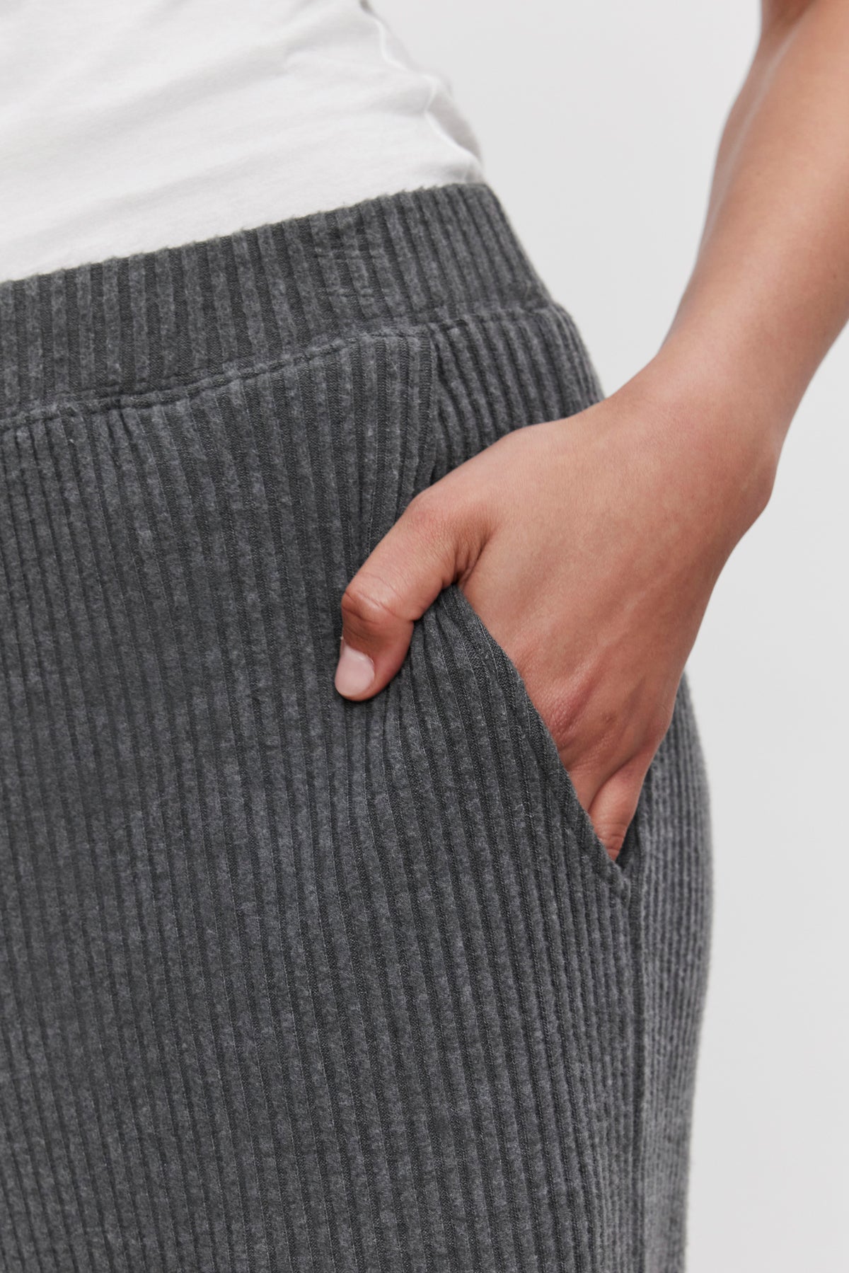   Close-up of a person wearing ultra-soft COLLEEN RIBBED PANT made from wide-leg, ribbed gray fabric by Velvet by Graham & Spencer, with their right hand placed in the pocket—perfect for everyday wear. 