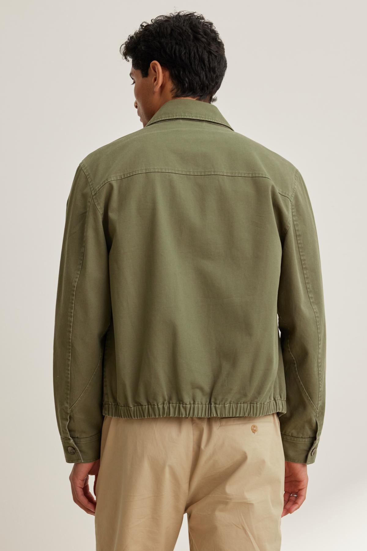   Man wearing the COLLINS JACKET by Velvet by Graham & Spencer with beige pants, viewed from the back against a neutral background. 