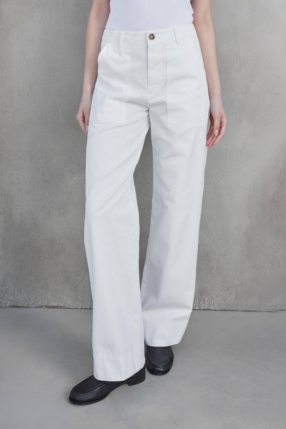   Person wearing high-waisted, wide-leg VENTURA PANT from Velvet by Jenny Graham, paired with a white top and black shoes, standing against a plain gray background. 