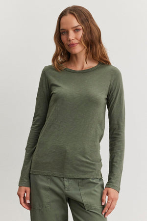 A person with long hair wears a LIZZIE TEE by Velvet by Graham & Spencer in green, complete with long sleeves and matching pants, standing against a plain background.