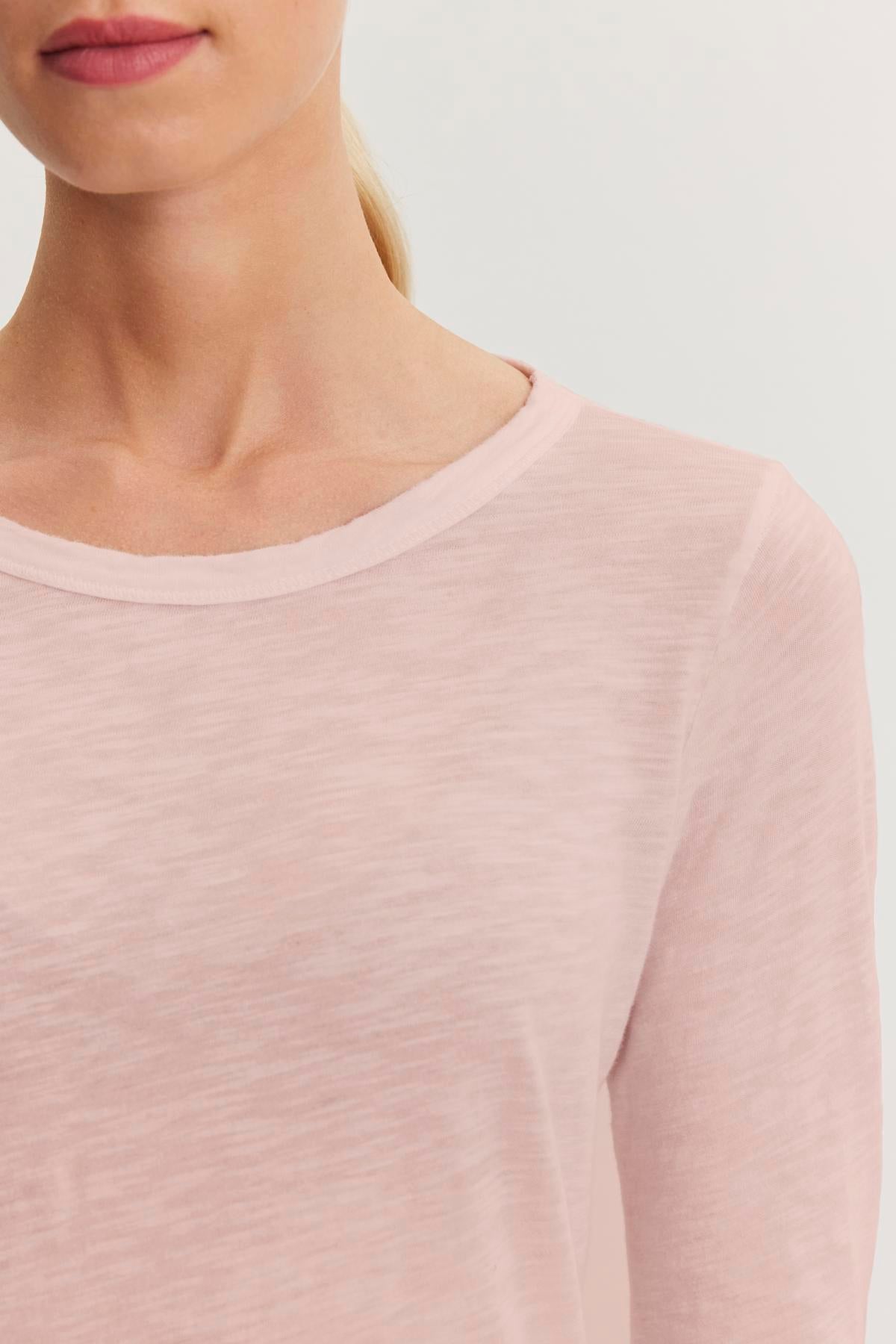 A person is wearing the LIZZIE TEE by Velvet by Graham & Spencer, a light pink cotton slub long sleeve shirt, with their upper chest and face partially out of frame.-38301515350209