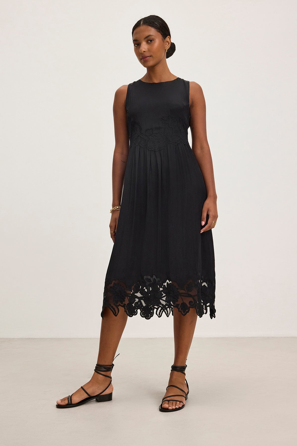 A person is wearing the BIANCA DRESS, a sleeveless black dress with floral lace at the hem by Velvet by Graham & Spencer, standing against a plain background.-38754087338177