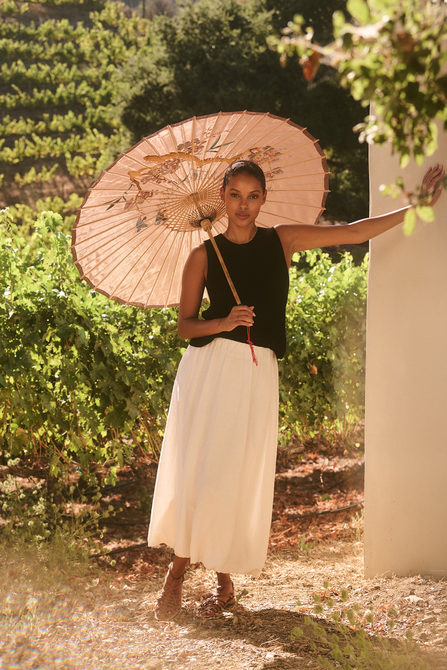 A woman standing outside with a parasol, wearing the Velvet by Graham & Spencer Muna top.