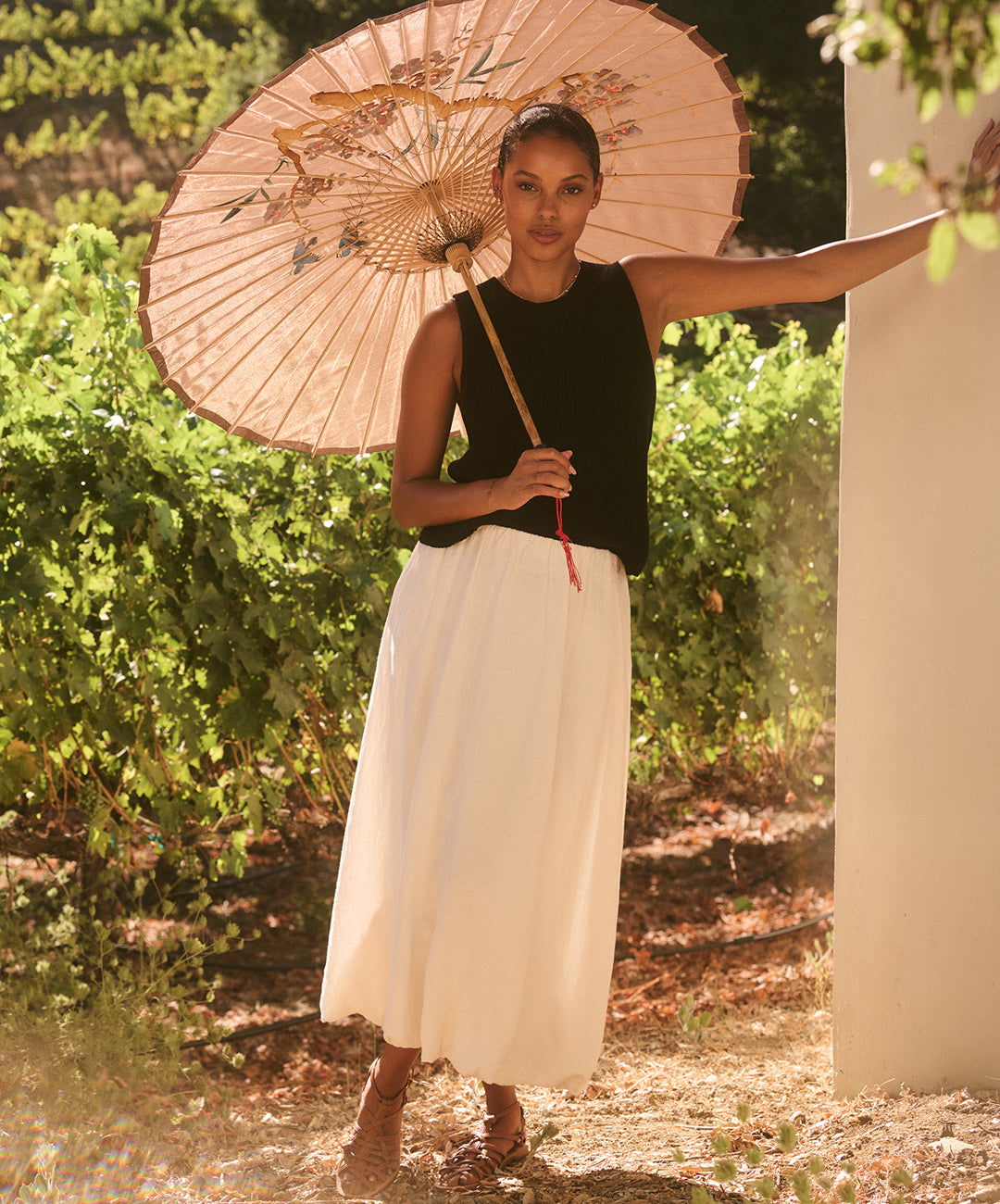 A woman standing outside with a parasol, wearing the Velvet by Graham & Spencer Muna top.