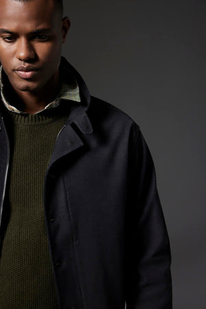 A person is shown from the shoulders up wearing a dark navy jacket over a green knit sweater and the WAYLON BUTTON-UP SHIRT by Velvet by Graham & Spencer, featuring a chest patch pocket, set against a plain dark background.