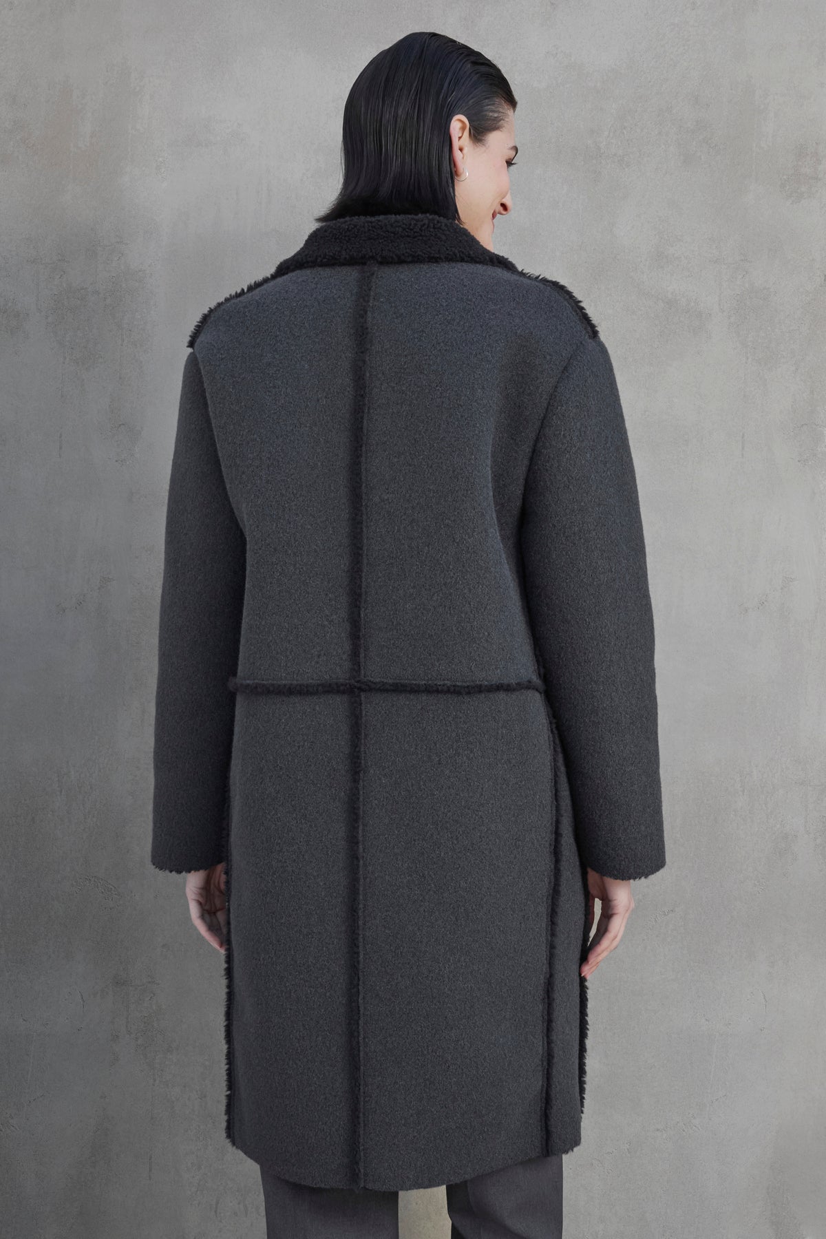 A person with dark hair wearing the ROSEMEAD COAT by Velvet by Jenny Graham stands facing away from the camera against a light grey textured background.-37659970437313