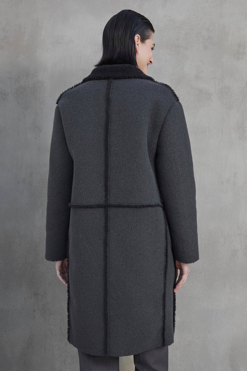 A person with dark hair wearing the ROSEMEAD COAT by Velvet by Jenny Graham stands facing away from the camera against a light grey textured background.