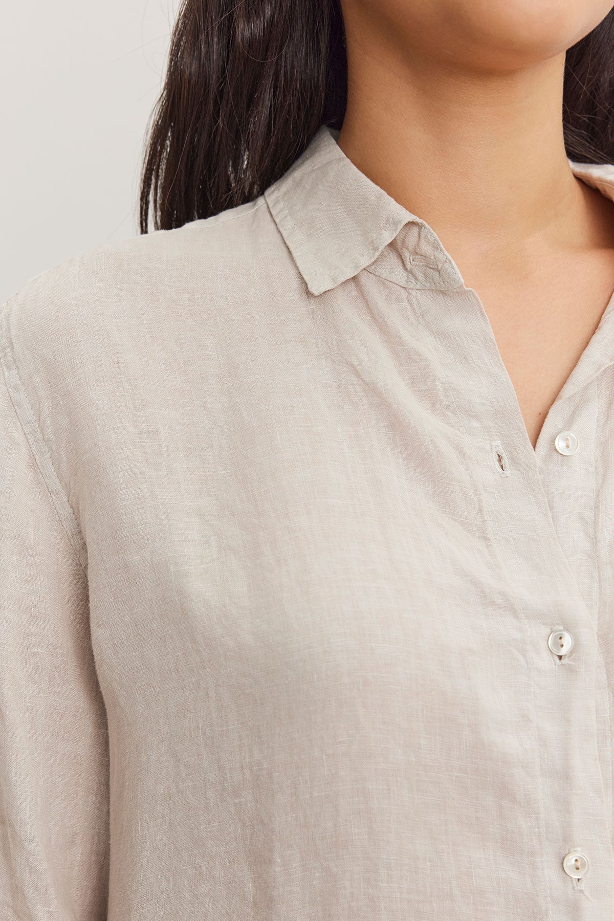   Close-up of a woman wearing a Velvet by Graham & Spencer WILLOW LINEN BUTTON-UP SHIRT with visible buttons and collar details. 