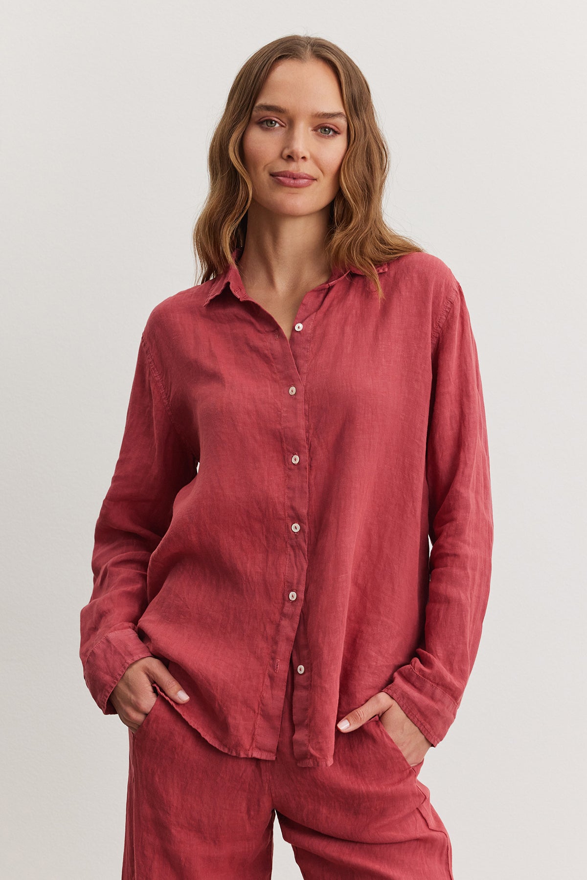   Woman in a casual red Willow Linen Button-Up shirt and matching pants, standing against a neutral background, looking directly at the camera with a slight smile. (Brand: Velvet by Graham & Spencer) 