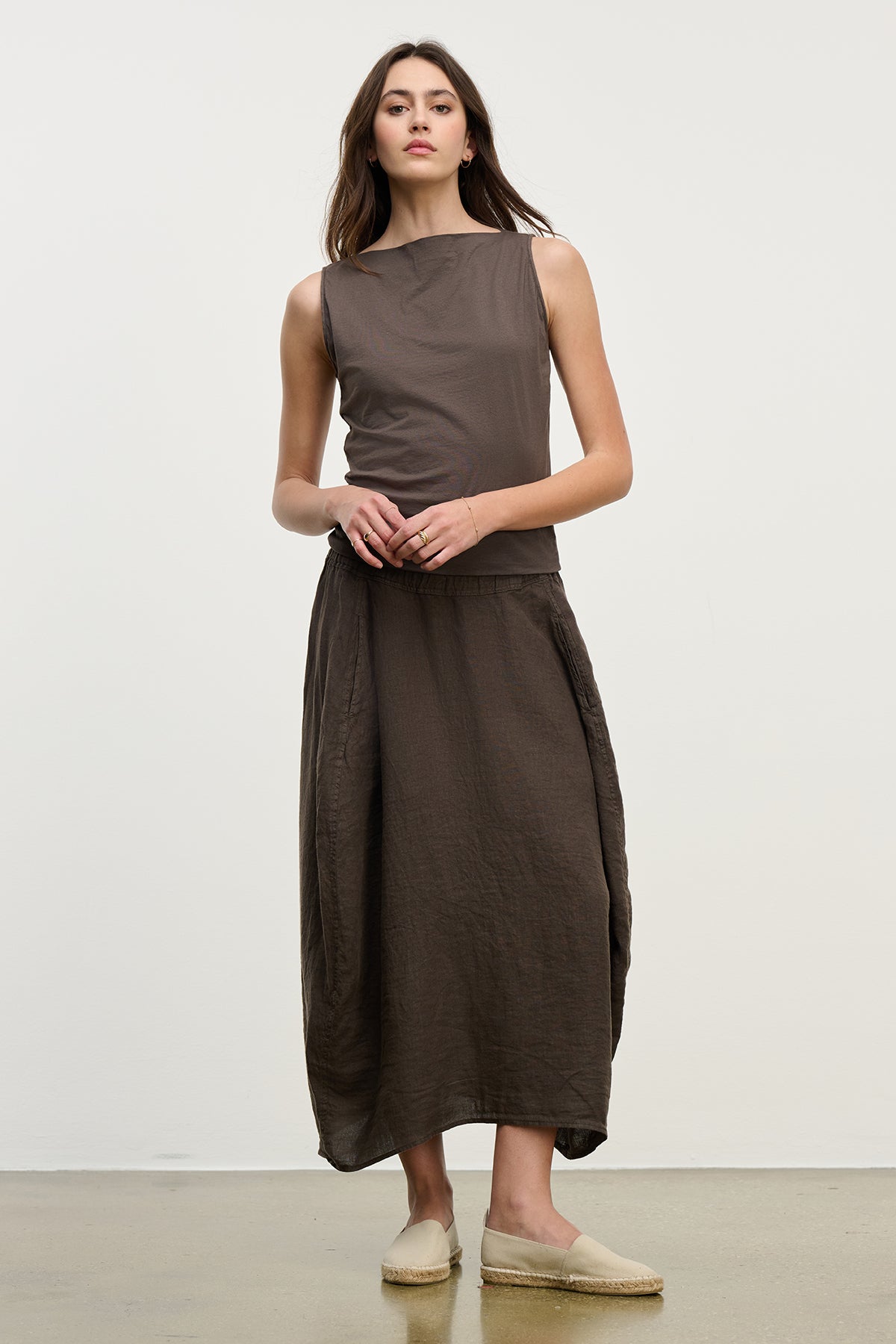   A person in a sleeveless brown top and Velvet by Graham & Spencer's FAE LINEN SKIRT featuring an elastic waistband stands against a plain background. 