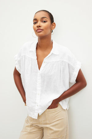 An individual wearing the ARIA LINEN TOP from Velvet by Graham & Spencer and beige pants stands against a plain light background.