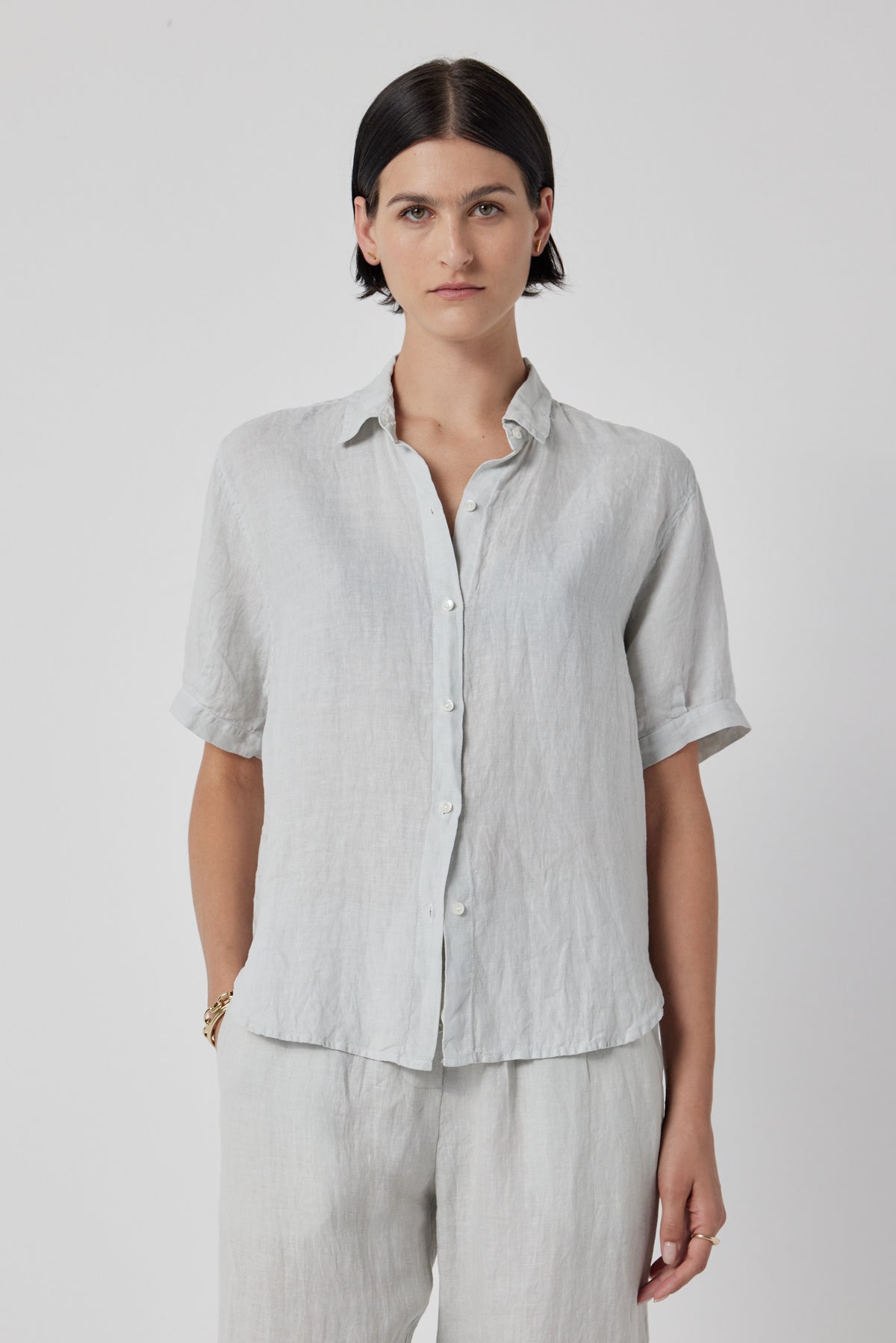   Woman in a casual CLAREMONT LINEN SHIRT by Velvet by Jenny Graham and trousers, standing against a plain white background. 