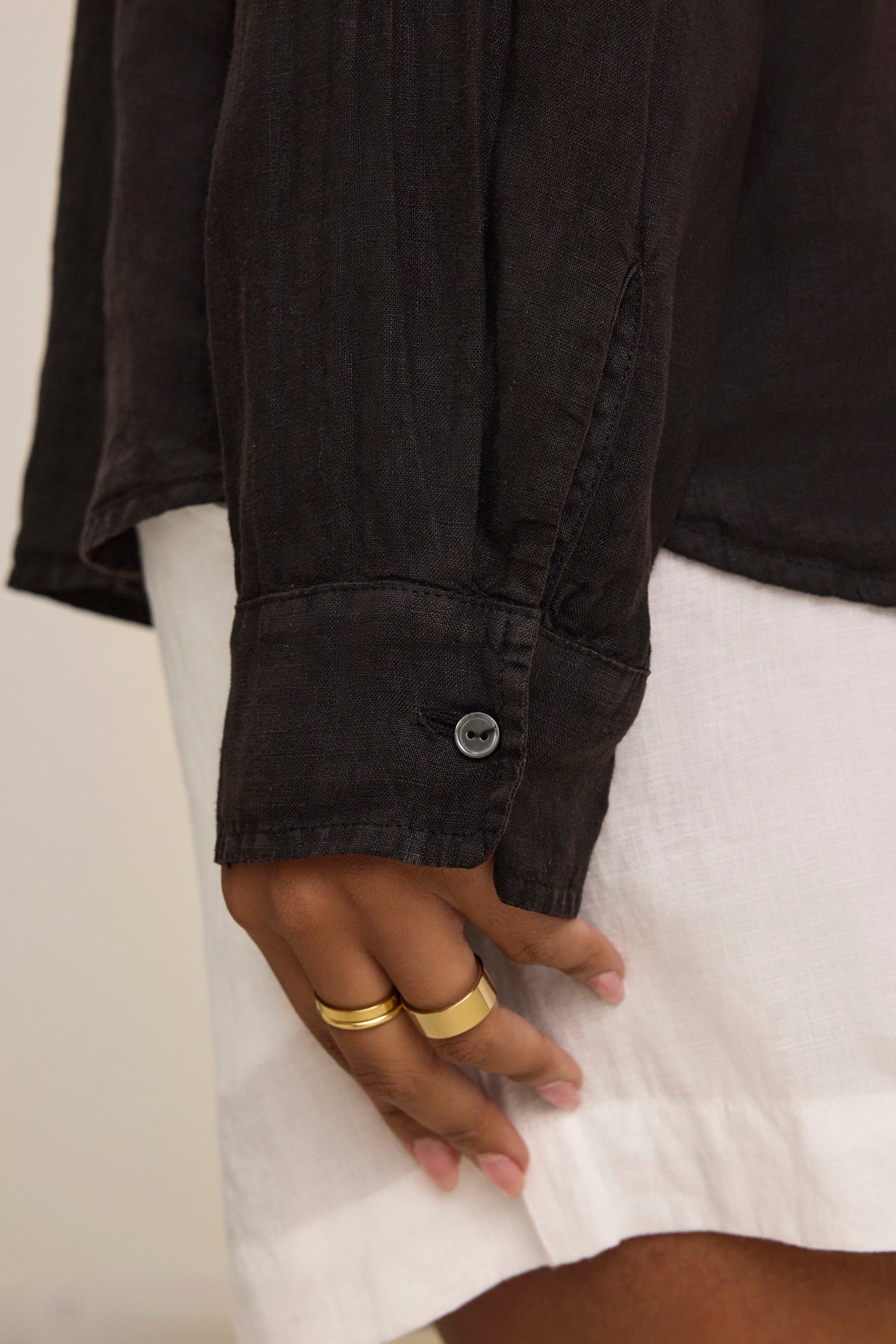   A close-up shows a hand with two gold rings against a black sleeve and the SISI LINEN SHIRT, a lightweight woven linen shirt by Velvet by Graham & Spencer. 