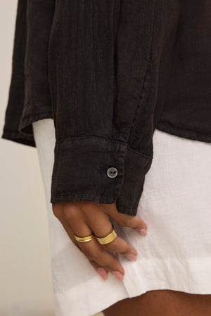 A close-up shows a hand with two gold rings against a black sleeve and the SISI LINEN SHIRT, a lightweight woven linen shirt by Velvet by Graham & Spencer.