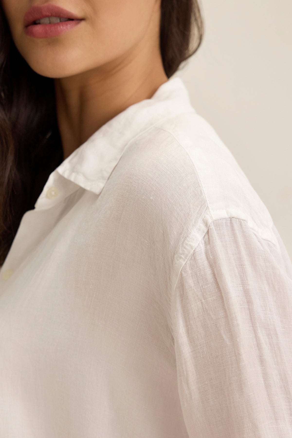   A person wearing a SISI LINEN SHIRT by Velvet by Graham & Spencer is partially visible, facing sideways. The focus is on the linen's texture and collar, highlighting its breathable fit. 