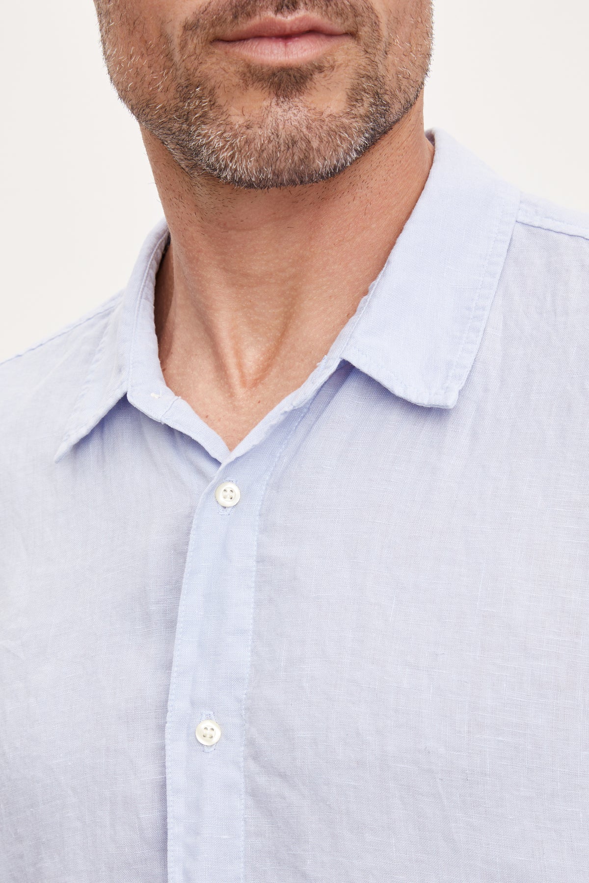 Close-up of a man wearing a Velvet by Graham & Spencer MACKIE LINEN BUTTON-UP SHIRT, focusing on the collar and top buttons.-36753546412225