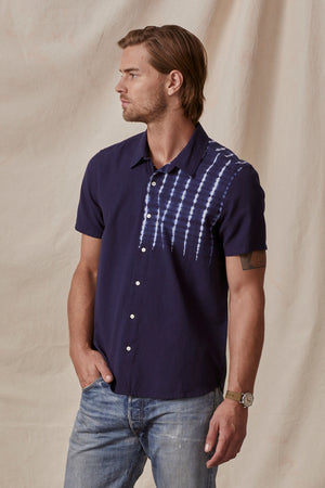 A man with light brown hair wearing a Velvet by Graham & Spencer RAFAEL button-up shirt with white tie-dye accents on the shoulders, standing against a beige background.