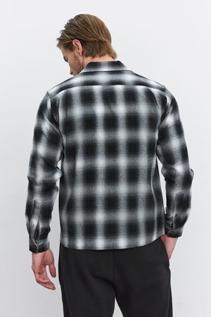 A person with light brown hair is wearing the Velvet by Graham & Spencer STANTON BUTTON-UP SHIRT in a black and white plaid ombre design, viewed from the back.