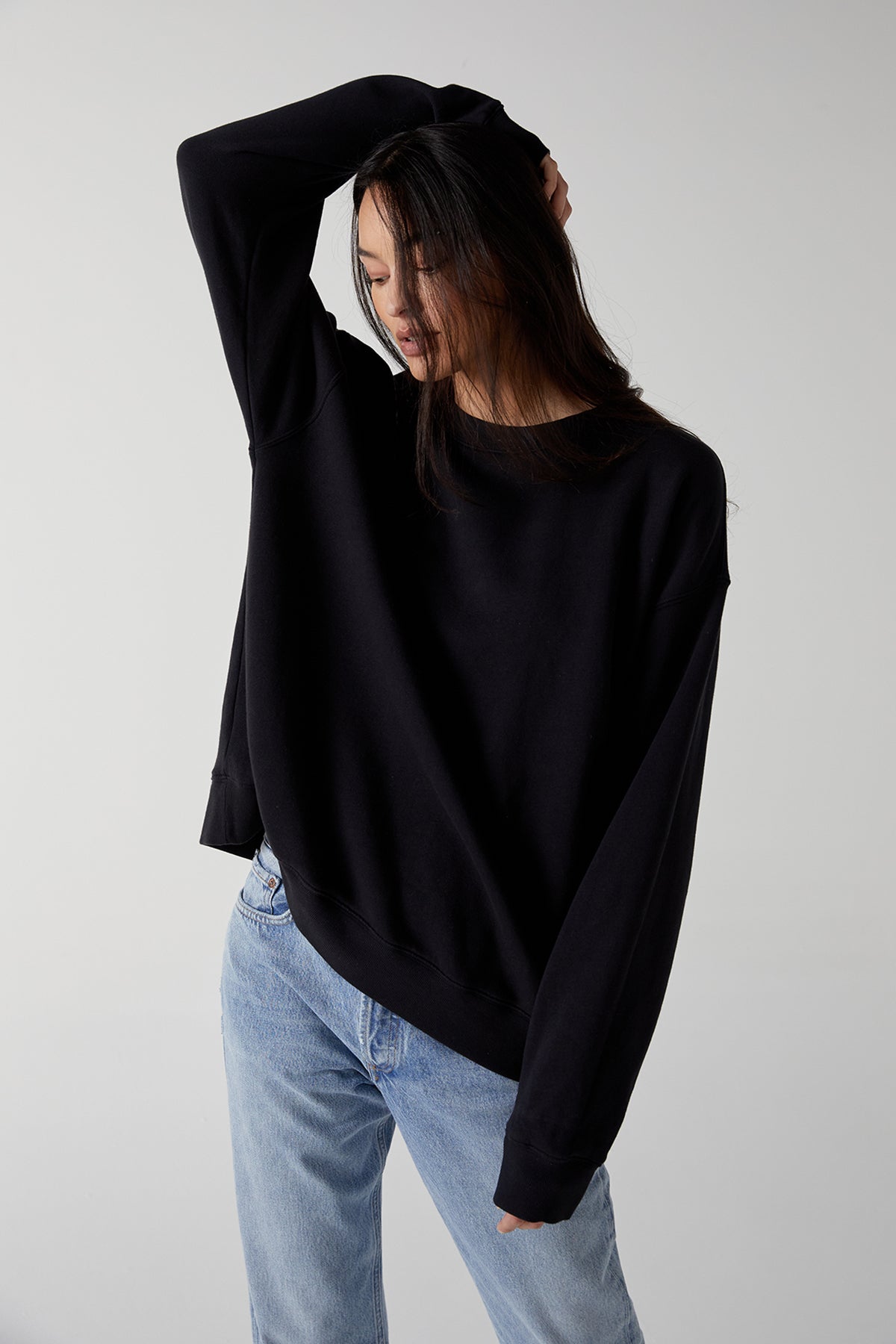   The model is wearing a black ABBOT SWEATSHIRT and jeans. 